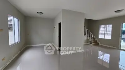 Spacious modern living room with glossy tile flooring and staircase in a contemporary home.