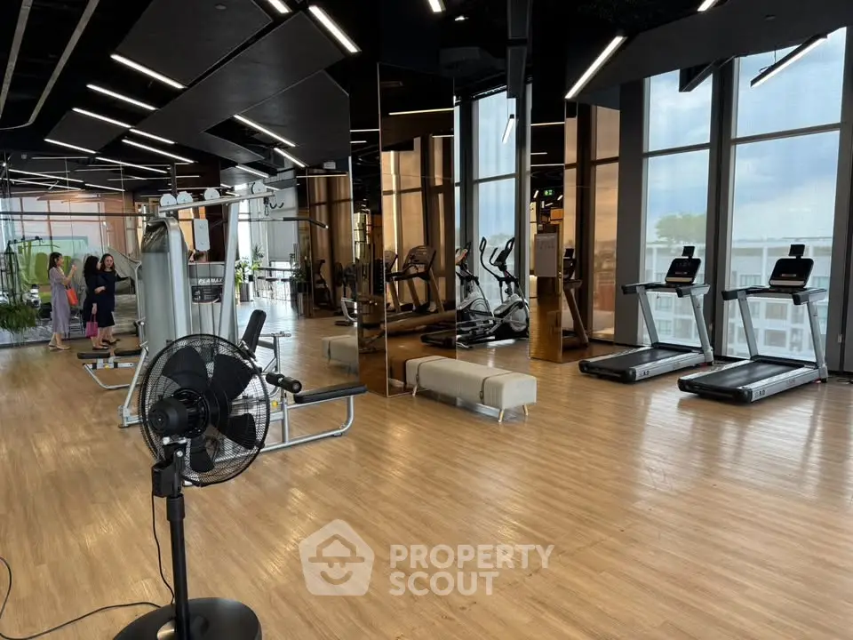 Spacious modern gym with state-of-the-art equipment and large windows offering a scenic view.