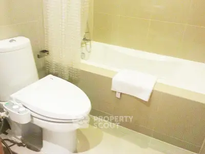 Modern bathroom with sleek toilet and bathtub, featuring elegant tile design.