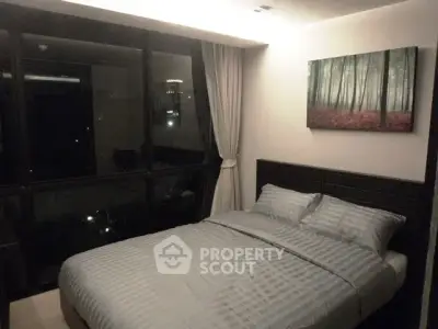 Cozy bedroom with large window and forest-themed artwork, offering a serene and inviting atmosphere.