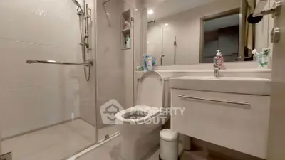 Modern bathroom with glass shower and sleek fixtures in contemporary apartment.