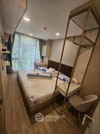 Modern bedroom with stylish decor and large window offering natural light.