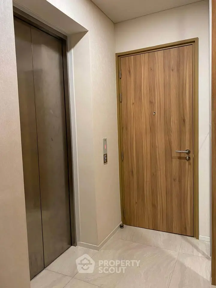 Modern apartment entrance with sleek elevator and wooden door