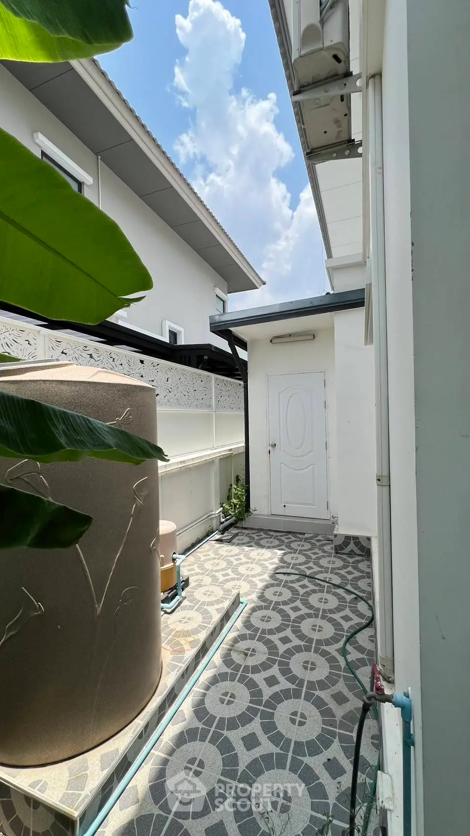 Charming exterior view of a modern home with tiled pathway and lush greenery.