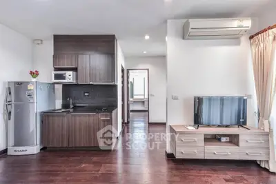 Modern apartment interior with sleek kitchen and cozy living area, featuring wooden flooring and stylish decor.