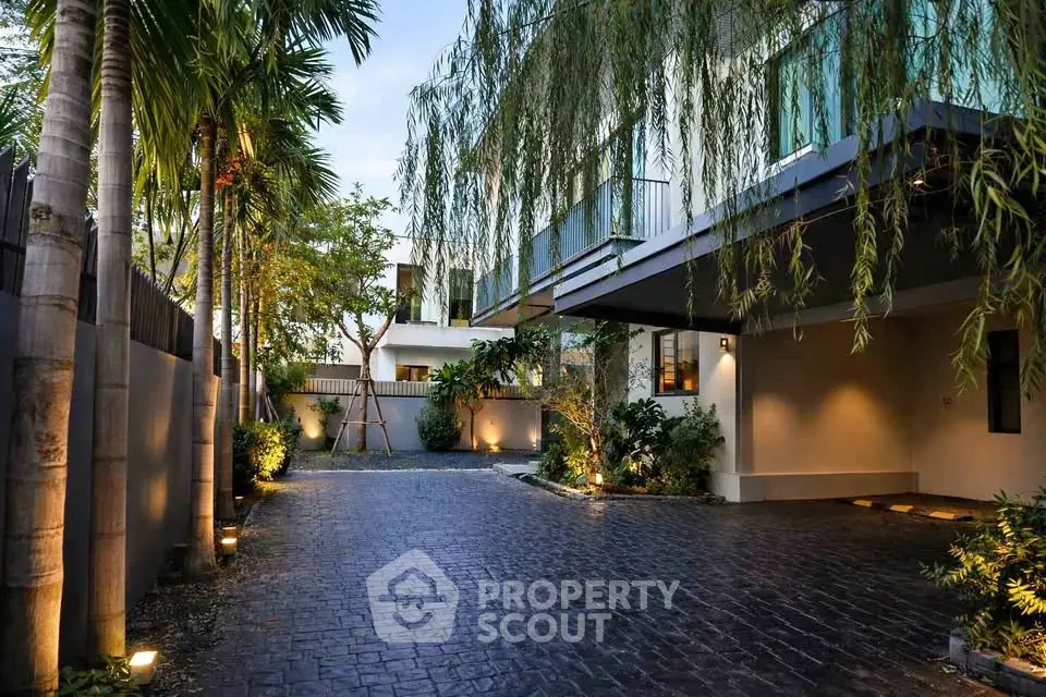 Luxurious modern building exterior with lush landscaping and elegant driveway lighting.
