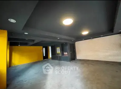 Spacious modern interior with bold yellow accent wall and sleek ceiling lights.