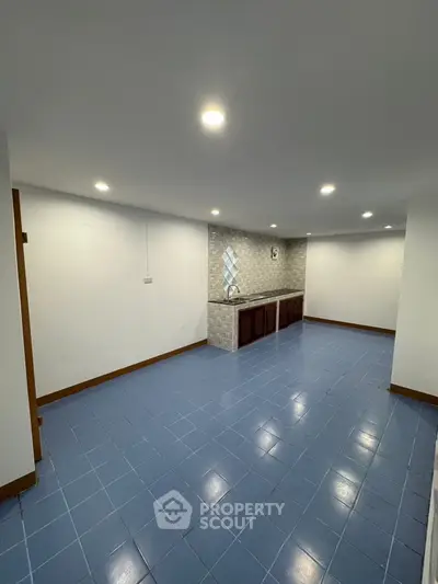 Spacious interior with blue tiled floor and recessed lighting, ideal for versatile use.