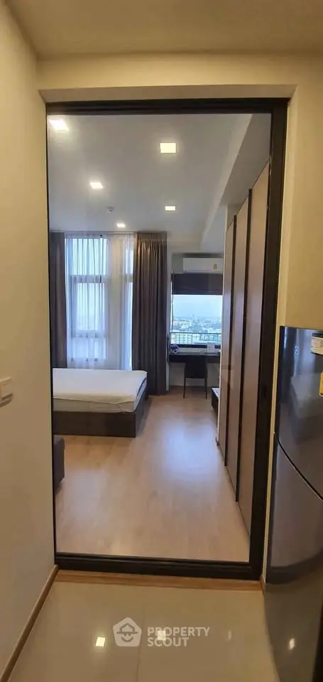 Modern bedroom with large window and sleek furnishings in a stylish apartment.