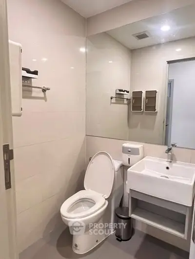 Modern bathroom with sleek fixtures and neutral tones, featuring a toilet and sink.