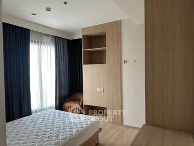 Modern bedroom with natural wood finishes and large window for ample light.