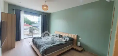 Spacious bedroom with modern decor and large window offering natural light