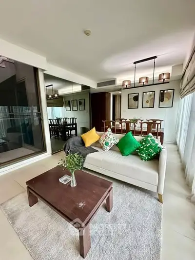 Spacious living room with modern decor and dining area, featuring large windows and stylish lighting.