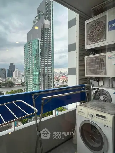 High-rise balcony with city view, featuring washing machine and air conditioning units.