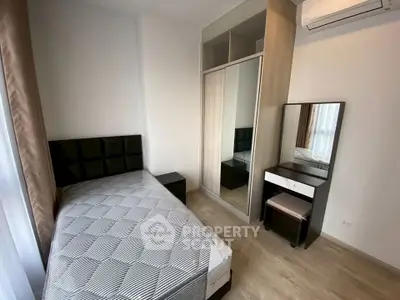 Modern bedroom with sleek design, featuring a single bed, mirrored wardrobe, and air conditioning.