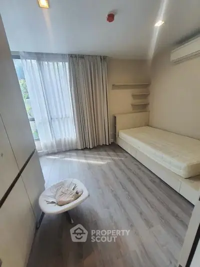 Bright and cozy bedroom with modern furnishings and large window for natural light.