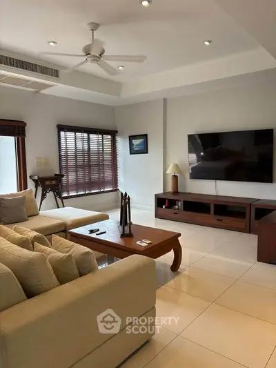 Spacious living room with modern decor and large TV, perfect for relaxation and entertainment.