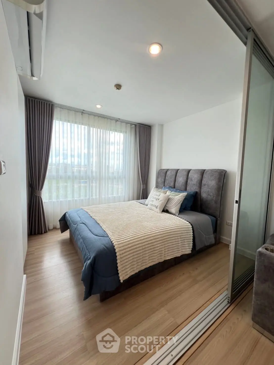 Modern bedroom with large window and stylish decor in a contemporary apartment.