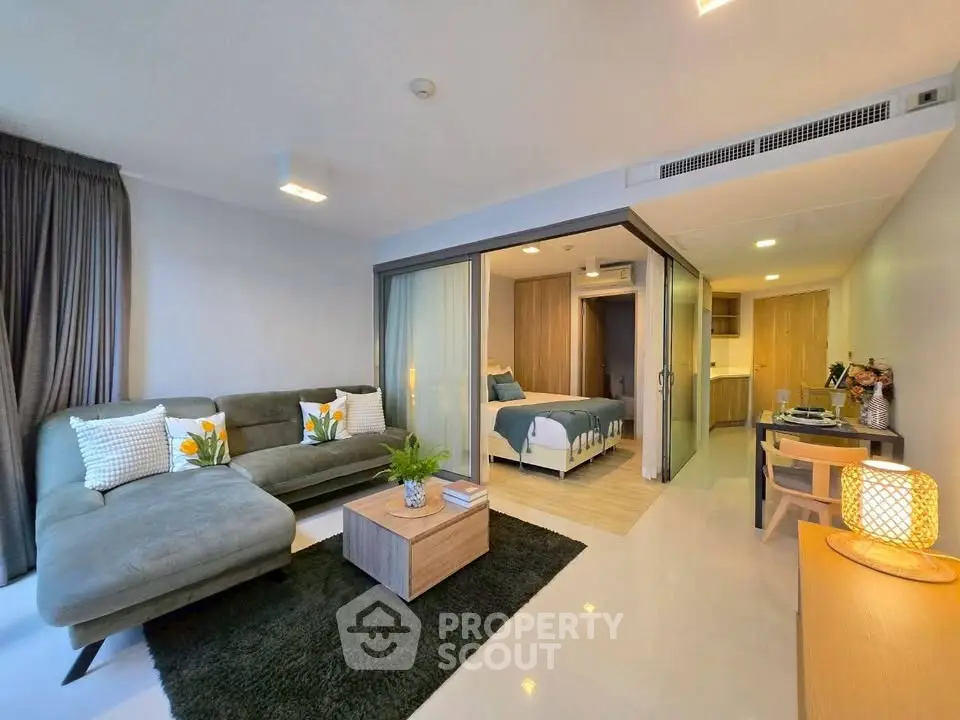 Modern open-plan living room with cozy seating and stylish bedroom in view.