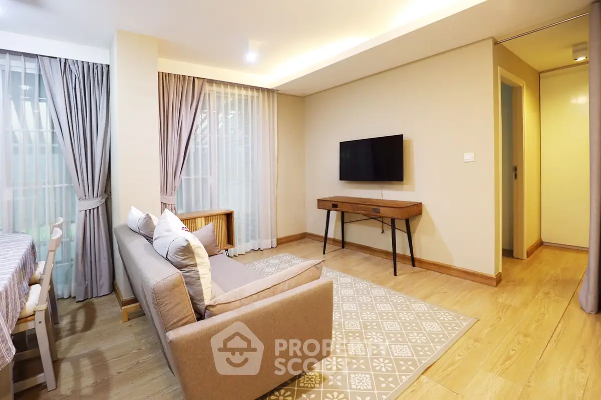 Modern living room with stylish decor and natural light, featuring a cozy sofa and wall-mounted TV.