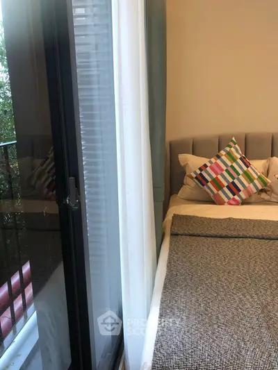 Cozy bedroom with colorful pillows and balcony view, perfect for relaxation.