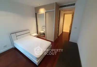 Spacious bedroom with hardwood floors and built-in closet in modern apartment.