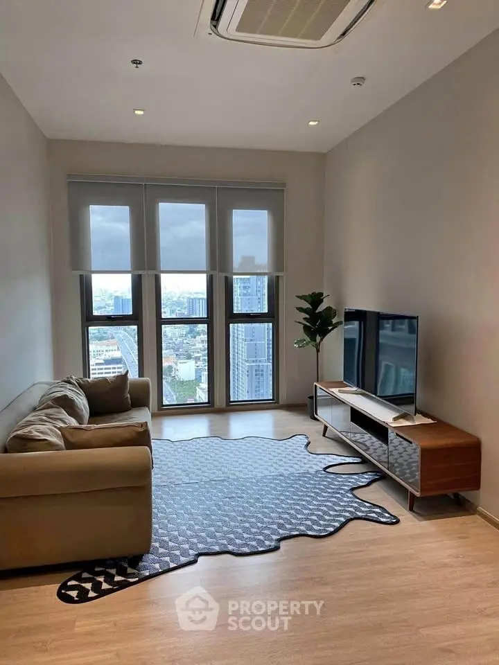 Modern living room with city view, cozy sofa, stylish rug, and sleek TV stand.