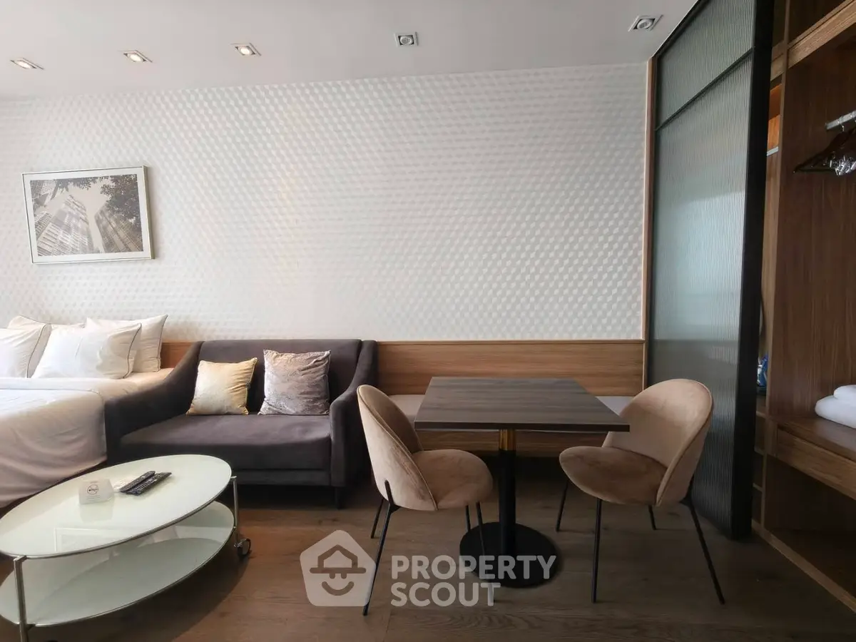 Modern studio apartment with cozy seating and dining area, featuring elegant decor and ample natural light.