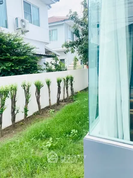 Modern residential exterior with lush garden and large windows in a serene neighborhood.