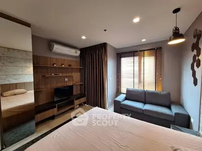 Modern bedroom with cozy sofa and stylish decor, featuring air conditioning and natural light.