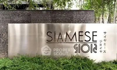 Elegant entrance sign of Siamese Gioia surrounded by lush greenery.