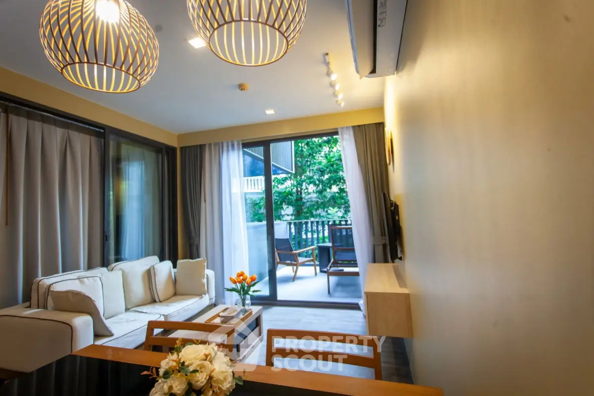 Modern living room with stylish lighting and access to a spacious balcony with greenery view.