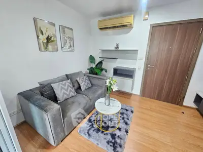 Modern living room with stylish decor and cozy gray sofa, featuring wooden flooring and air conditioning.