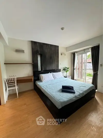 Spacious bedroom with modern decor and large window offering natural light