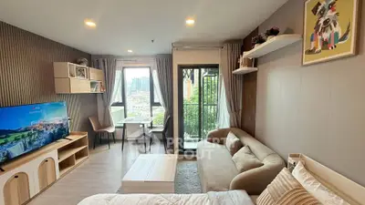 Modern living room with cozy sofa, wall-mounted TV, and city view from large window.