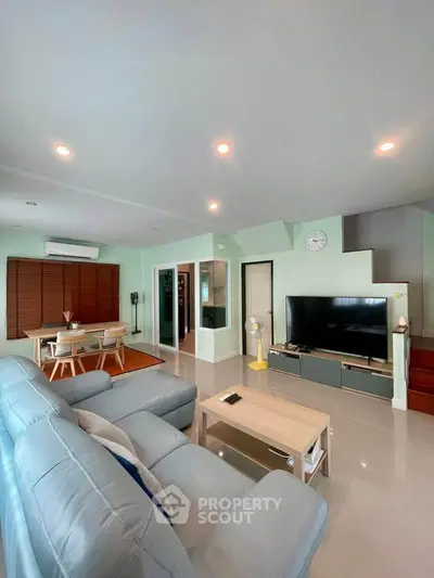 Spacious living room with modern decor and large TV, ideal for family gatherings.