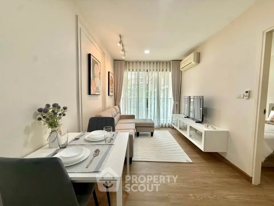 Modern living room with stylish decor and natural light, featuring a cozy dining area and sleek furniture.