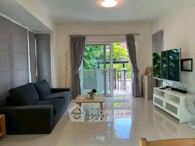 Spacious living room with modern decor and large windows opening to a lush garden view.