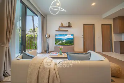 Modern living room with stylish decor and large TV, featuring a cozy sofa and natural light from large windows.