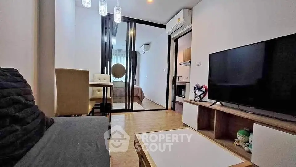 Modern living room with sleek furniture and open layout, featuring a large TV and stylish decor.