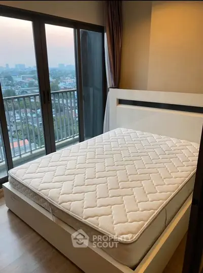 Modern bedroom with large windows and city view, featuring a comfortable bed and elegant decor.
