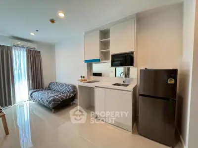 Modern kitchen with sleek appliances and cozy living area in a stylish apartment.