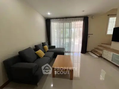 Spacious living room with modern gray sofas and wooden coffee table, featuring large windows for natural light.