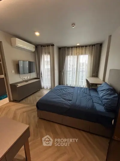 Modern bedroom with stylish decor, featuring a cozy bed, wall-mounted TV, and elegant curtains.