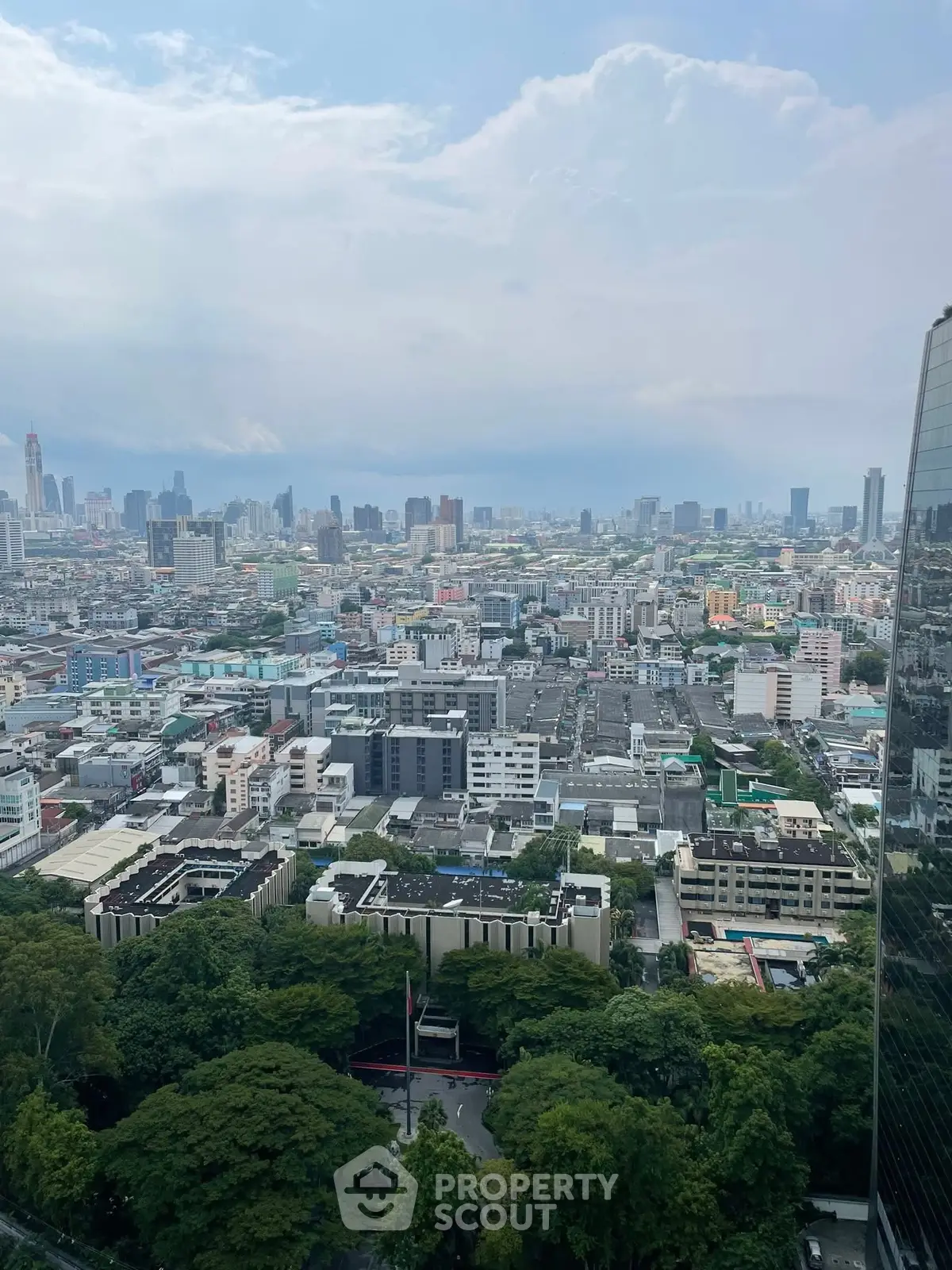 Stunning cityscape view from a high-rise building showcasing urban skyline and lush greenery.