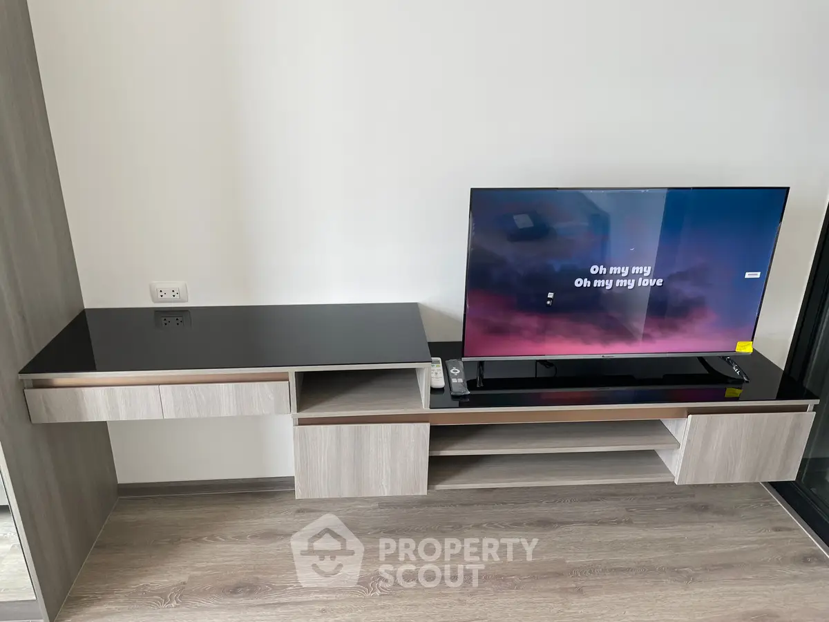 Modern living room with sleek TV stand and flat-screen TV displaying song lyrics.