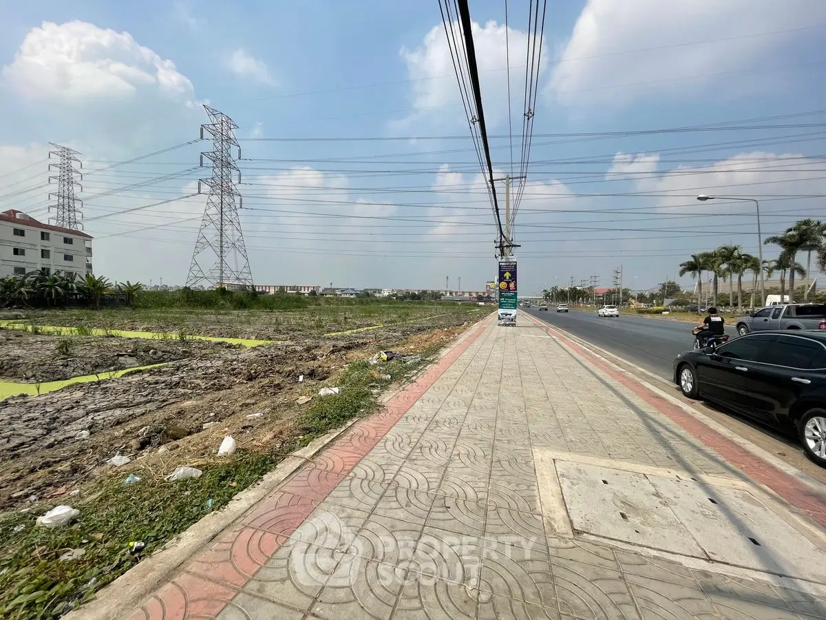 Expansive roadside land plot with development potential under clear blue skies.
