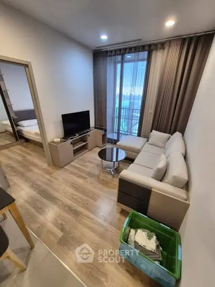 Modern living room with cozy sofa, TV, and balcony access in stylish apartment.