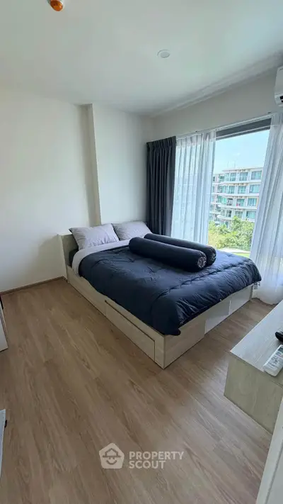 Modern bedroom with large window and stylish decor in a high-rise apartment.