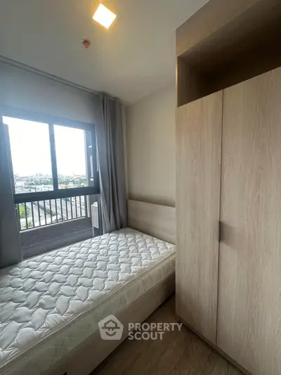 Cozy bedroom with large window offering stunning city views, featuring a comfortable bed and ample wardrobe space.